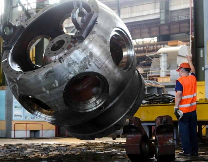 a worker helping crane operator lower larger machinery