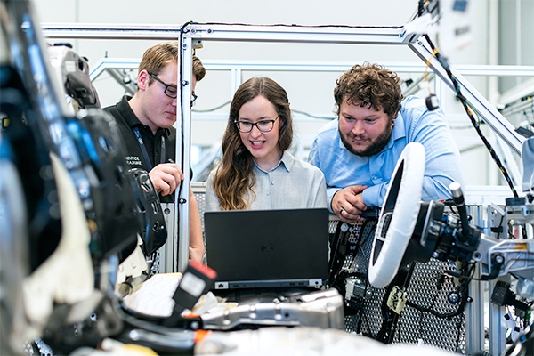 Employees gather round a laptop