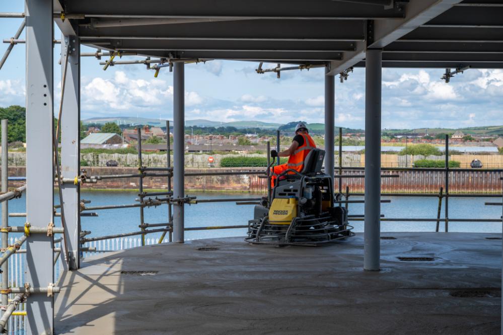 A workman driving a piece of machinery working on the University of Cumbria Barrow campus under construction in 2024